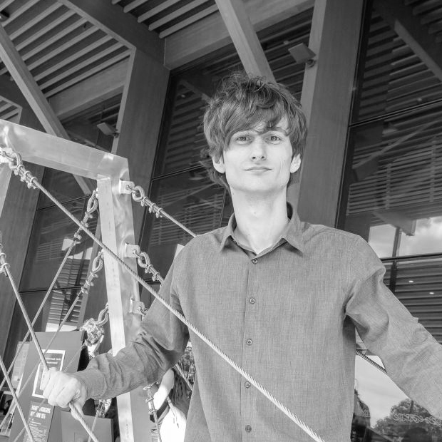 Lucus Mactier standing on a model suspension bridge he designed.